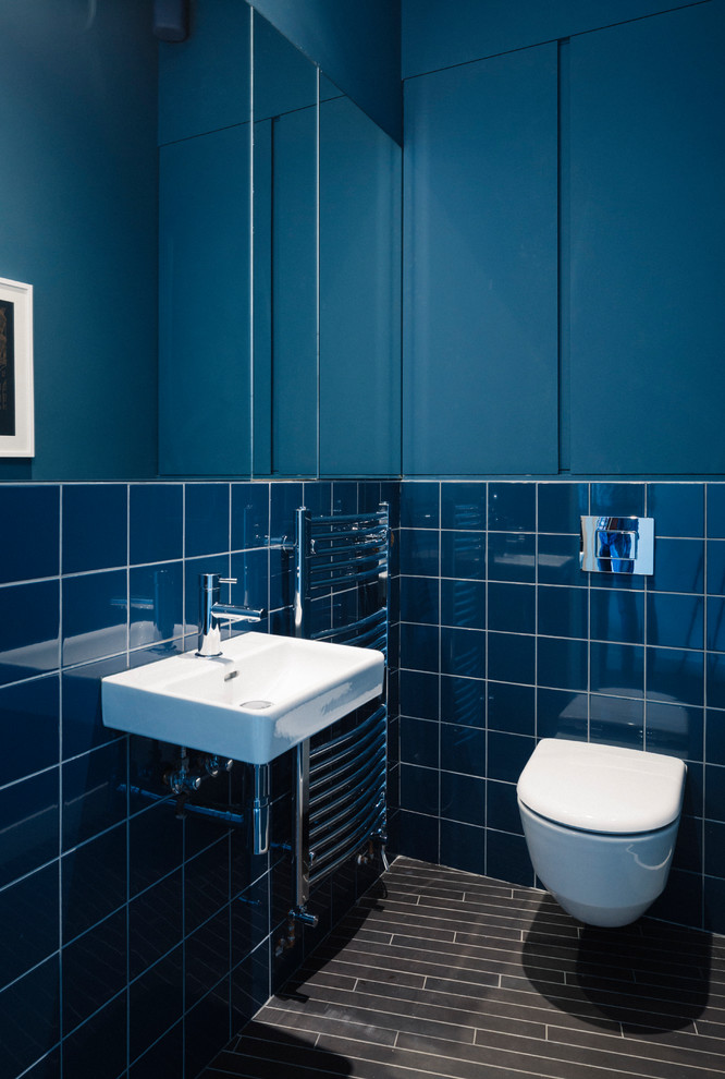 Design ideas for a small contemporary powder room in London with a wall-mount toilet, blue tile, porcelain tile, blue walls, porcelain floors, a wall-mount sink and black floor.