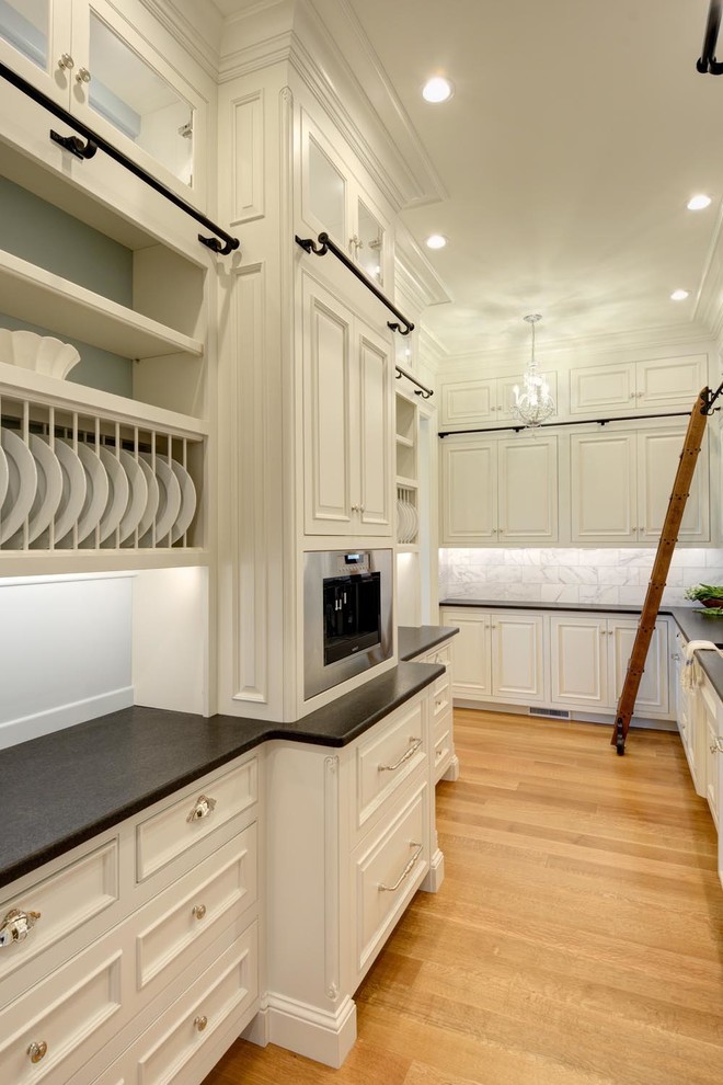 This is an example of a large traditional galley kitchen pantry in Boston with a single-bowl sink, glass-front cabinets, white cabinets, grey splashback, stone tile splashback, stainless steel appliances, medium hardwood floors and quartzite benchtops.
