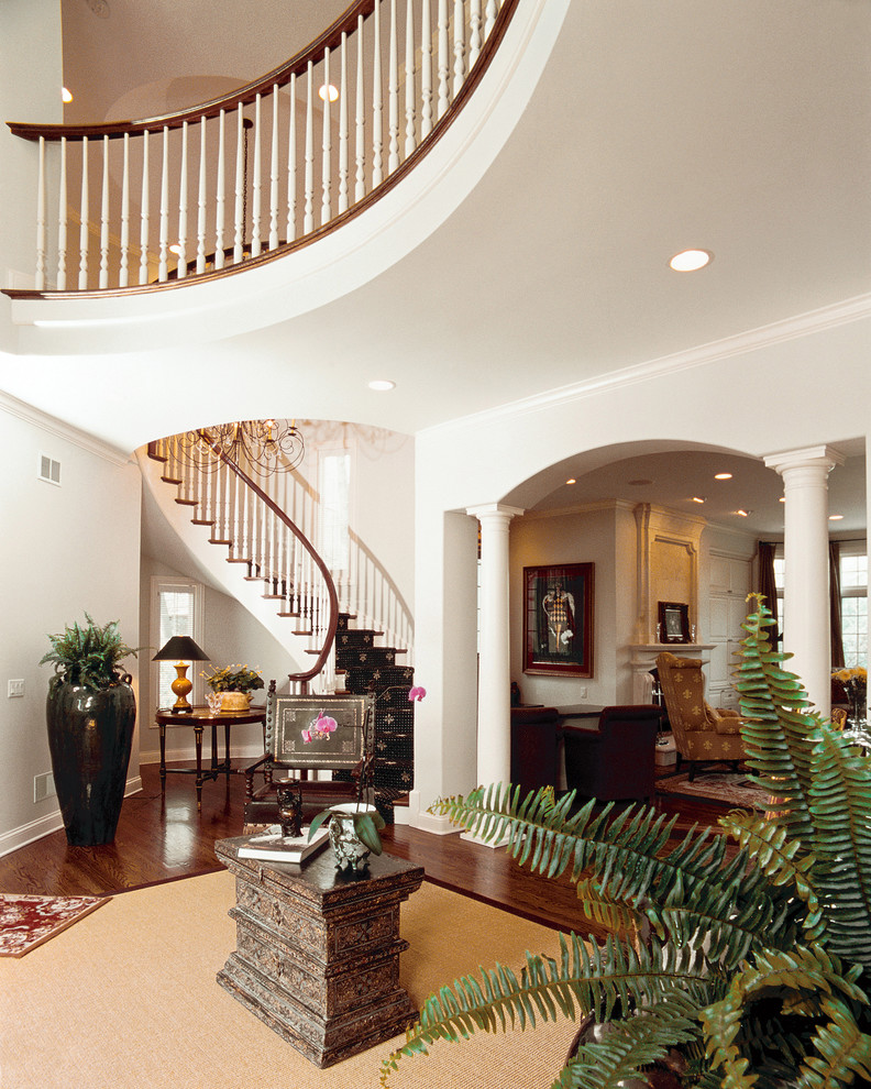 Foyer Features Floating Curved Staircase with Round Columns and