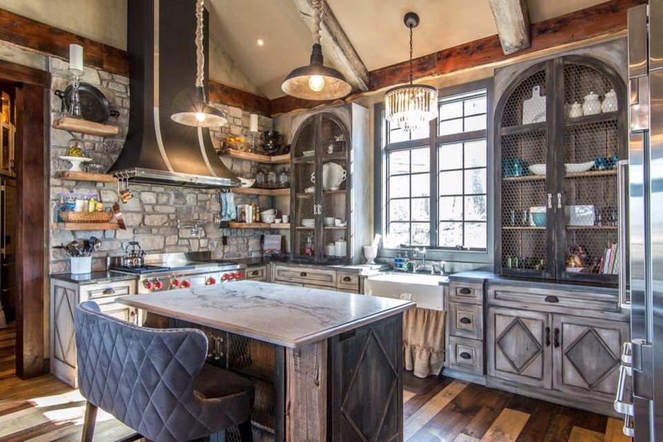 Inspiration for a mid-sized rustic l-shaped medium tone wood floor and brown floor eat-in kitchen remodel in St Louis with a farmhouse sink, distressed cabinets, gray backsplash, stainless steel appliances, an island, raised-panel cabinets and marble countertops