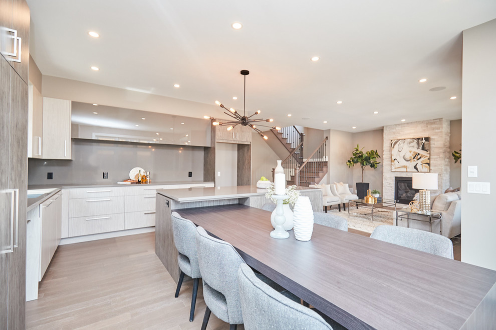 Large transitional l-shaped medium tone wood floor and gray floor eat-in kitchen photo with an undermount sink, flat-panel cabinets, gray cabinets, quartzite countertops, gray backsplash, stainless steel appliances, an island and gray countertops