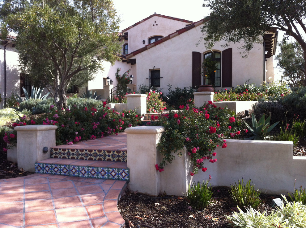 Design ideas for a mid-sized mediterranean front yard full sun garden in Orange County with a garden path and natural stone pavers.