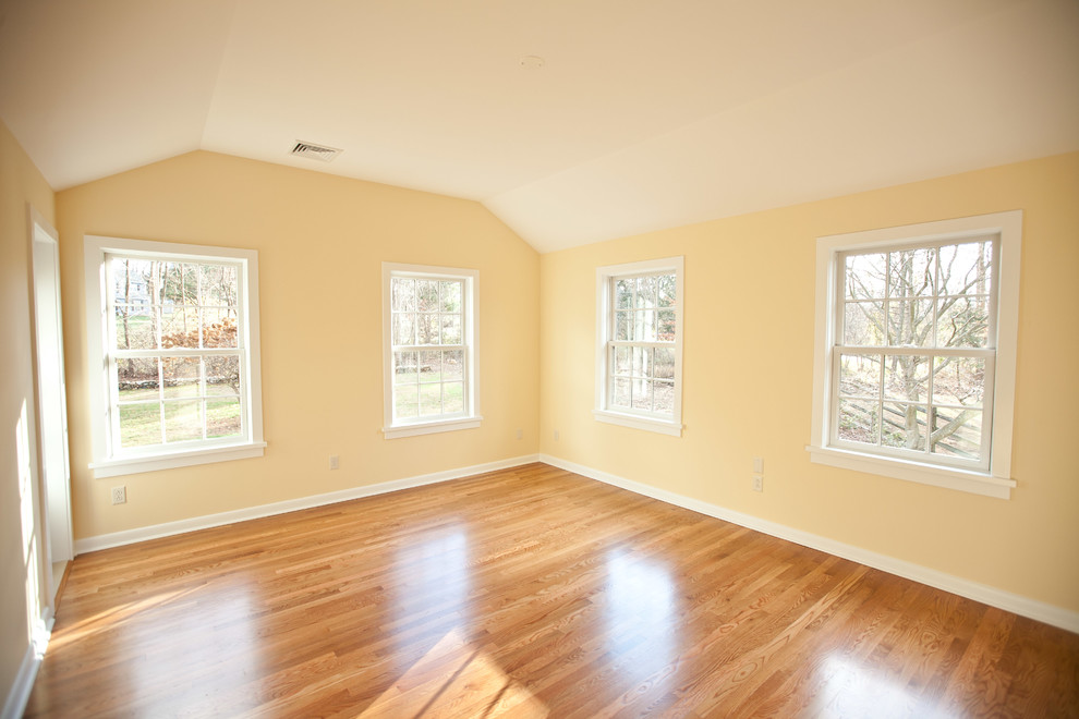 This is an example of a mid-sized transitional bedroom in Philadelphia with yellow walls, light hardwood floors, no fireplace and beige floor.