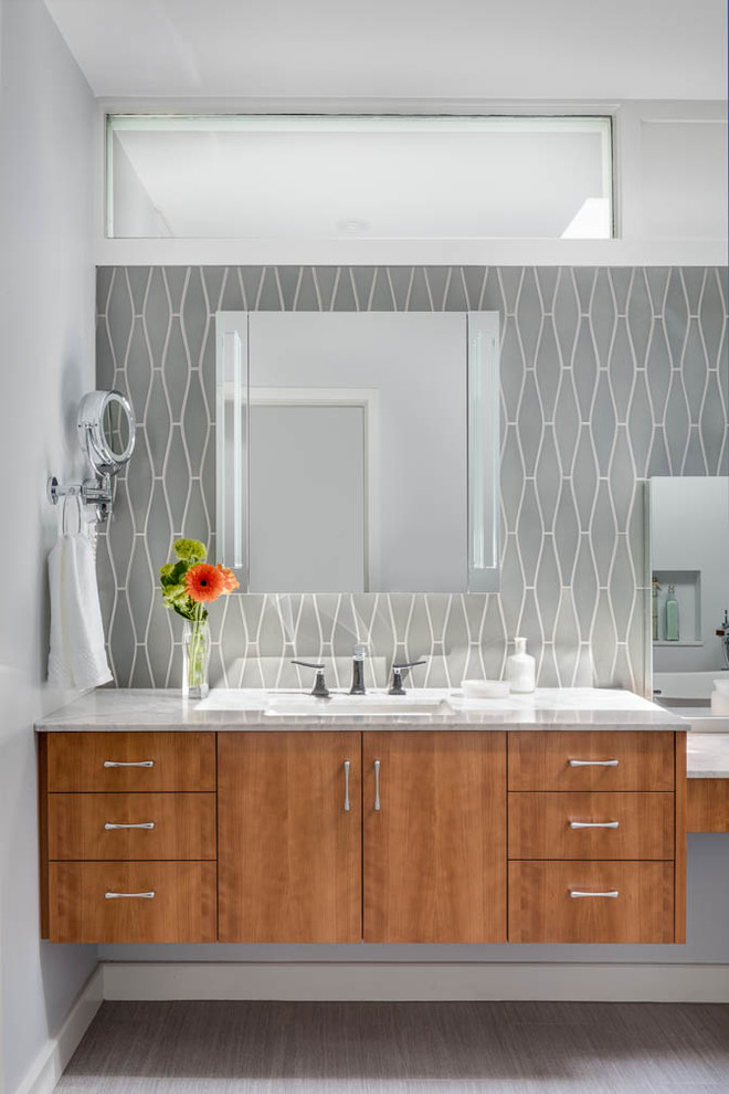 Design ideas for a large midcentury bathroom in Boston with flat-panel cabinets, medium wood cabinets, a freestanding tub, a corner shower, gray tile, glass tile, grey walls, ceramic floors, an undermount sink, marble benchtops, grey floor and a hinged shower door.