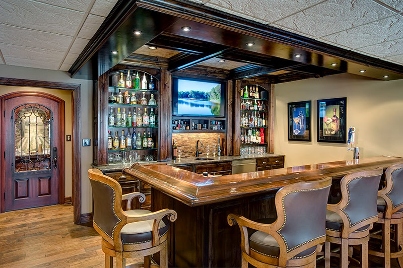 This is an example of a large arts and crafts home bar in Kansas City with dark hardwood floors and brown floor.
