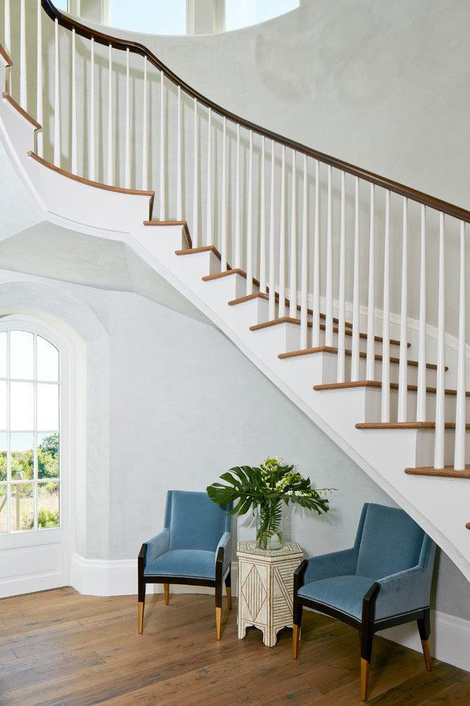 This is an example of a mid-sized beach style wood curved staircase in Charleston with wood risers and wood railing.