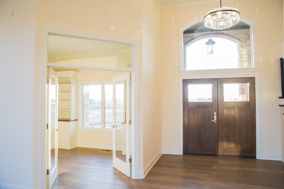 Photo of a large traditional front door in Indianapolis with beige walls, medium hardwood floors, a double front door, a medium wood front door, brown floor and coffered.
