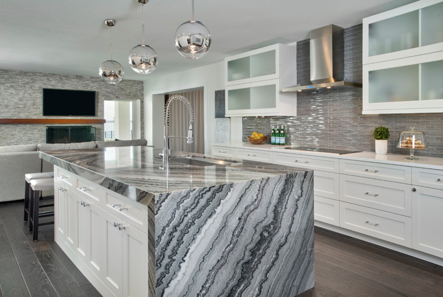 Inspiration for a mid-sized contemporary galley open plan kitchen in Tampa with an undermount sink, shaker cabinets, white cabinets, glass tile splashback, stainless steel appliances, dark hardwood floors, marble benchtops, grey splashback, brown floor and with island.