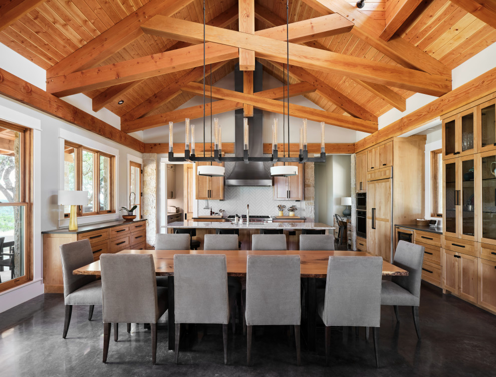 Country open plan dining in Austin with white walls, concrete floors, black floor, exposed beam, vaulted and wood.