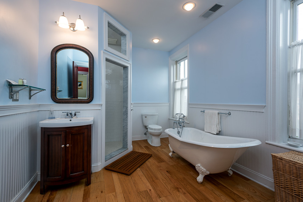 This is an example of a mid-sized modern master bathroom in New York with a claw-foot tub, an alcove shower, blue walls and light hardwood floors.