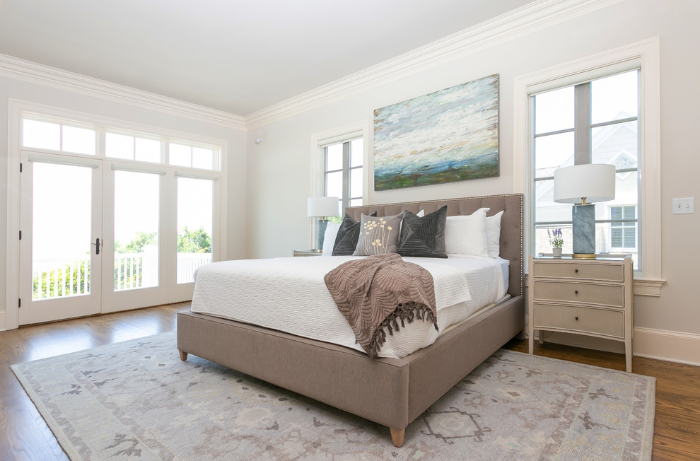 Photo of a large beach style master bedroom in Charleston with grey walls, medium hardwood floors and brown floor.