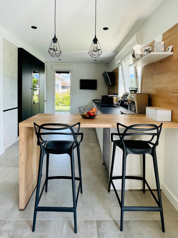 Inspiration for a large contemporary galley open plan kitchen with an integrated sink, all styles of cabinet, black cabinets, marble worktops, wood splashback, integrated appliances, ceramic flooring, grey floors, black worktops and a breakfast bar.