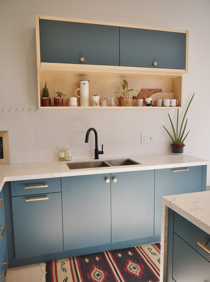 Inspiration for a mid-sized modern l-shaped eat-in kitchen in Toronto with an undermount sink, flat-panel cabinets, green cabinets, quartz benchtops, white splashback, mosaic tile splashback, stainless steel appliances, light hardwood floors and with island.