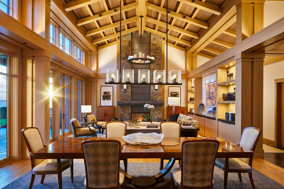 This is an example of a large transitional open plan dining in Seattle with medium hardwood floors, a stone fireplace surround, vaulted, beige walls, a standard fireplace and brown floor.