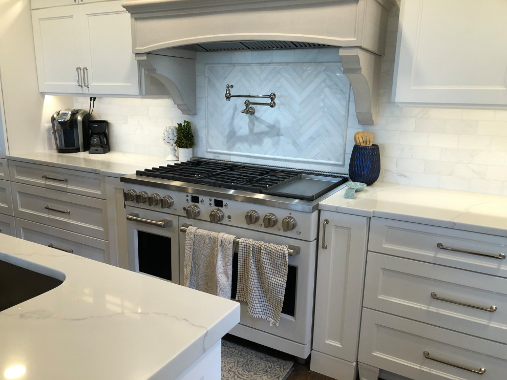 Large transitional l-shaped medium tone wood floor and brown floor eat-in kitchen photo in Baltimore with a farmhouse sink, flat-panel cabinets, white cabinets, quartz countertops, white backsplash, subway tile backsplash, stainless steel appliances, an island and white countertops