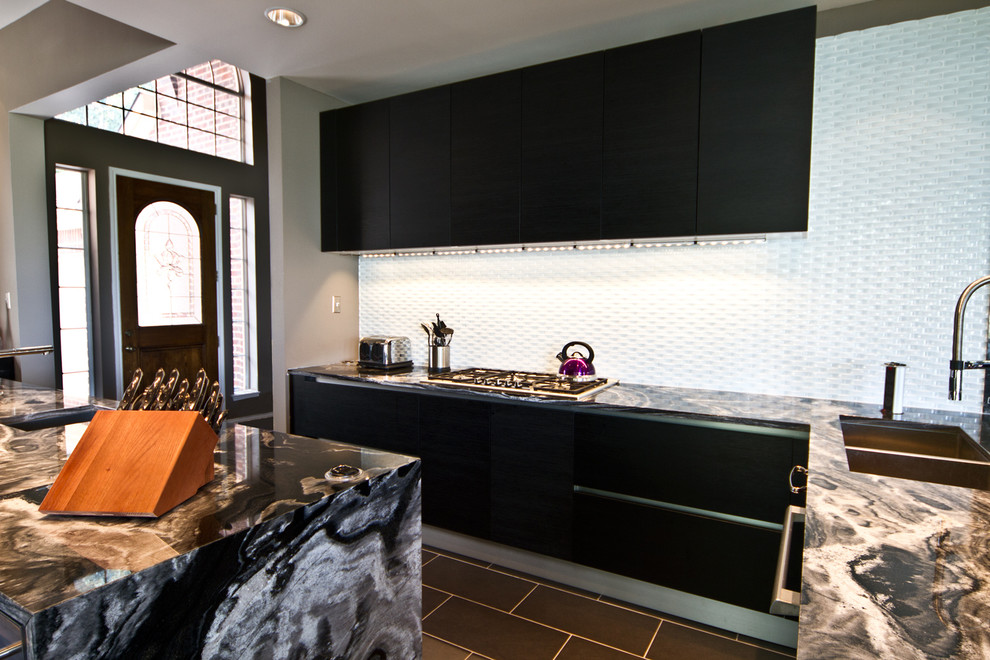 This is an example of a contemporary galley eat-in kitchen in Dallas with an undermount sink, flat-panel cabinets, dark wood cabinets, granite benchtops, white splashback, stainless steel appliances and glass tile splashback.