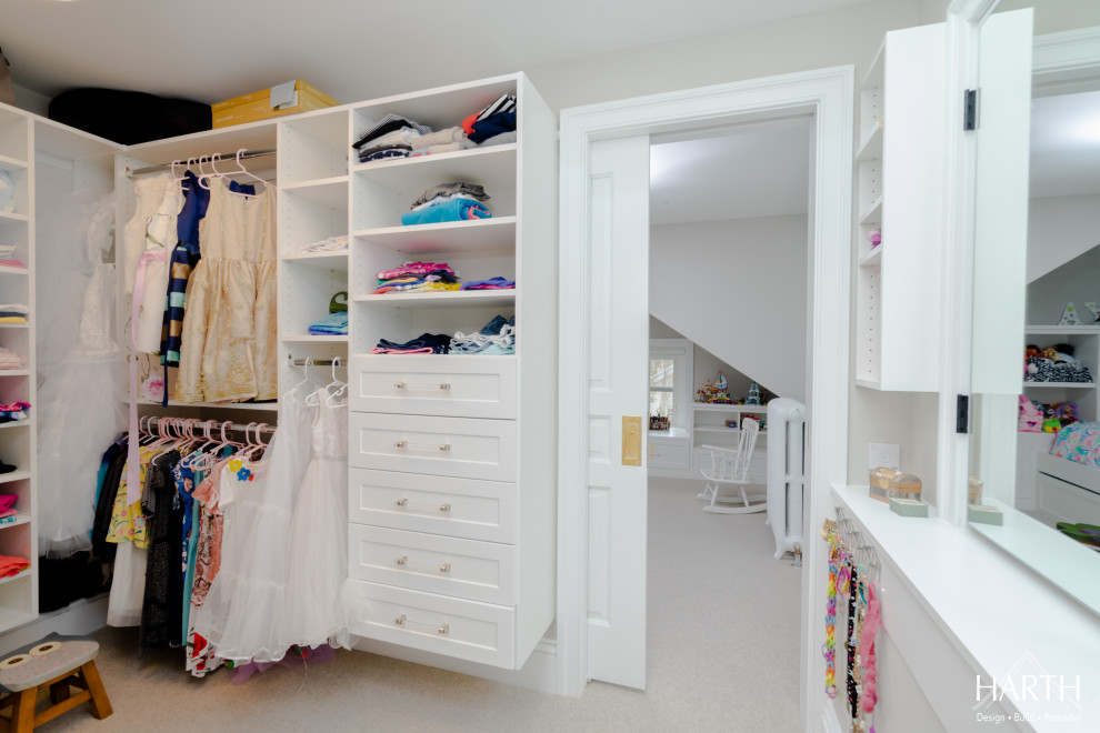 This is an example of a mid-sized transitional women's walk-in wardrobe in Philadelphia with shaker cabinets, white cabinets, carpet, beige floor and vaulted.