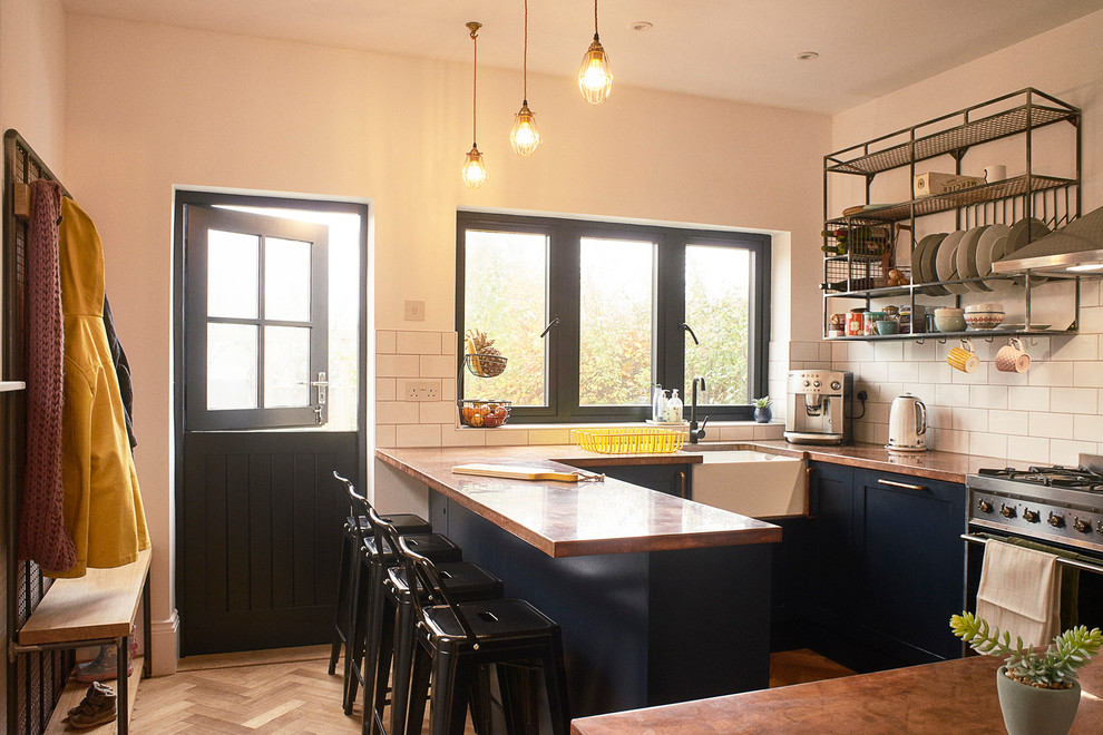 Small industrial u-shaped separate kitchen in Sussex with a farmhouse sink, shaker cabinets, blue cabinets, copper benchtops, white splashback, subway tile splashback and stainless steel appliances.