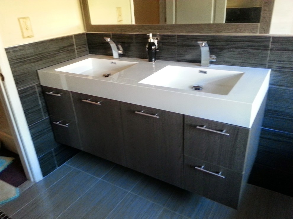 This is an example of a mid-sized modern master bathroom in New York with flat-panel cabinets, dark wood cabinets, a freestanding tub, brown tile, porcelain tile, beige walls, porcelain floors, an integrated sink, solid surface benchtops and beige floor.