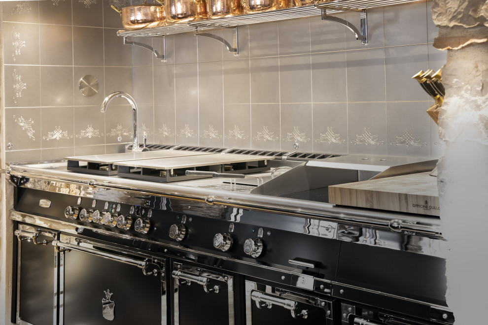 Immagine di una grande cucina ad U eclettica chiusa con lavello integrato e top in acciaio inossidabile