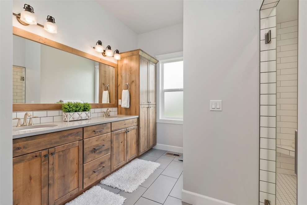 This is an example of a mid-sized traditional bathroom in Boise with recessed-panel cabinets, medium wood cabinets, an open shower, a one-piece toilet, white tile, subway tile, grey walls, laminate floors, an undermount sink, quartzite benchtops, a hinged shower door, grey benchtops, a single vanity, a built-in vanity and grey floor.