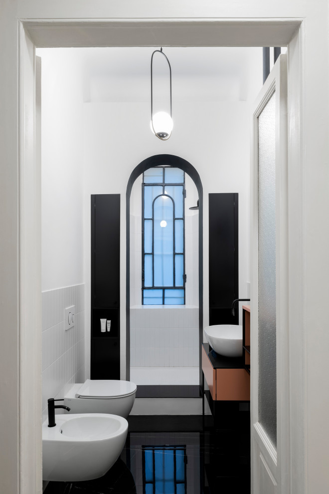 Inspiration for a mid-sized scandinavian 3/4 bathroom in Milan with shaker cabinets, an open shower, a wall-mount toilet, white tile, ceramic tile, white walls, porcelain floors, a vessel sink, glass benchtops, black floor, an open shower, black benchtops, a niche, a single vanity and a freestanding vanity.
