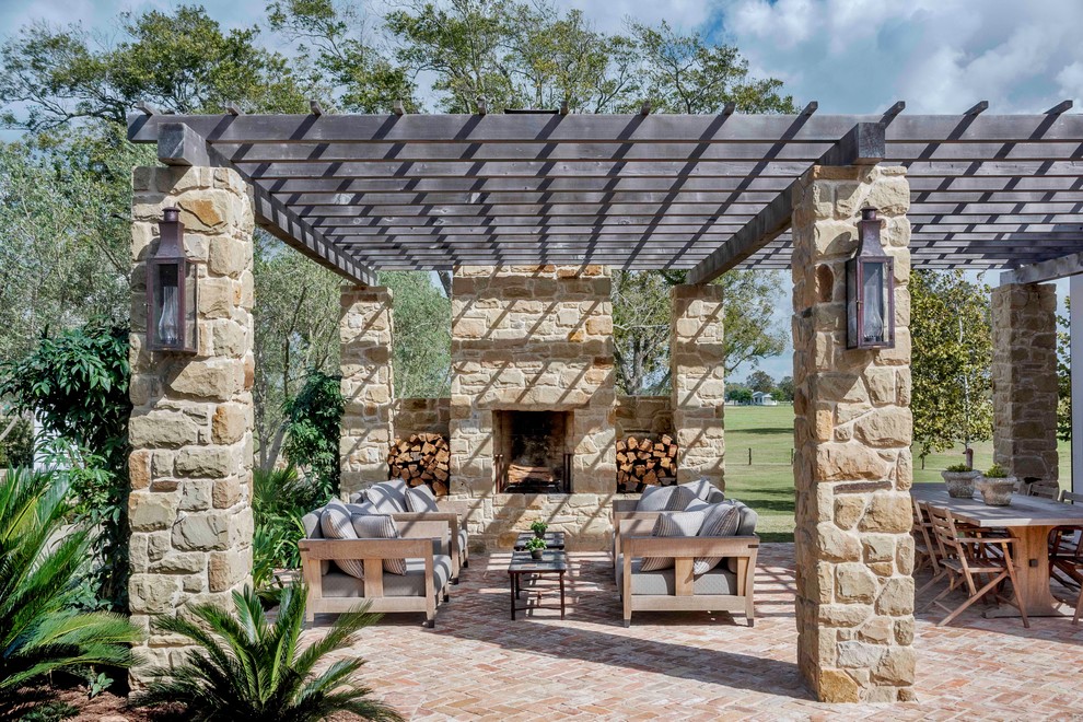 Large country backyard patio in Houston with brick pavers, a pergola and with fireplace.