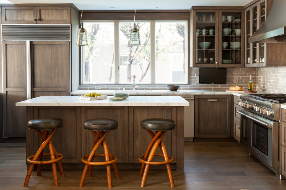 Inspiration for a transitional l-shaped dark wood floor kitchen remodel in San Francisco with glass-front cabinets, dark wood cabinets, marble countertops, gray backsplash, subway tile backsplash, paneled appliances and an island
