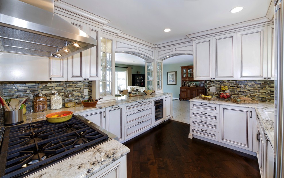 This is an example of a mid-sized traditional u-shaped kitchen pantry in Miami with an undermount sink, recessed-panel cabinets, white cabinets, granite benchtops, multi-coloured splashback, glass tile splashback, stainless steel appliances, a peninsula and dark hardwood floors.