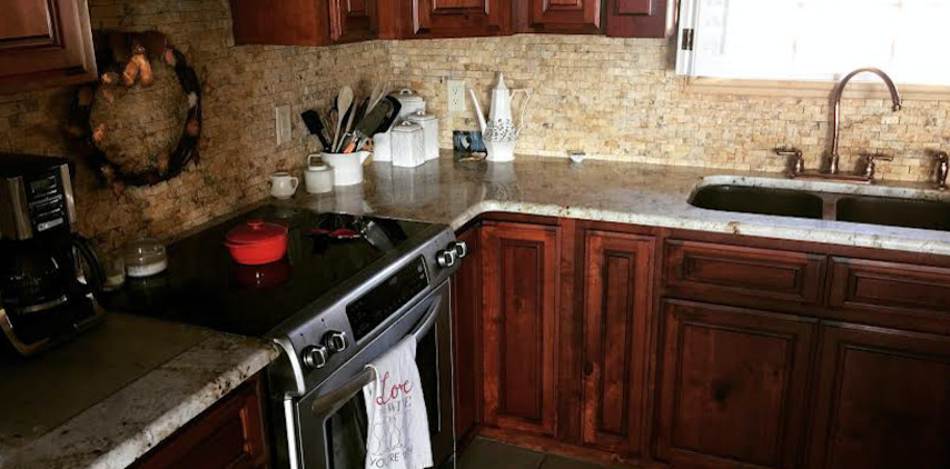 Mid-sized transitional l-shaped porcelain tile enclosed kitchen photo in Austin with a double-bowl sink, beaded inset cabinets, dark wood cabinets, granite countertops, beige backsplash, stone tile backsplash, stainless steel appliances and a peninsula