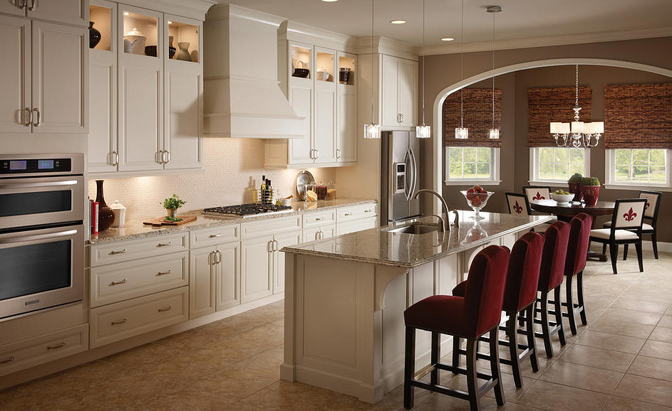 Inspiration for a large transitional galley ceramic tile and beige floor eat-in kitchen remodel in Orlando with an undermount sink, raised-panel cabinets, white cabinets, granite countertops, stainless steel appliances and an island