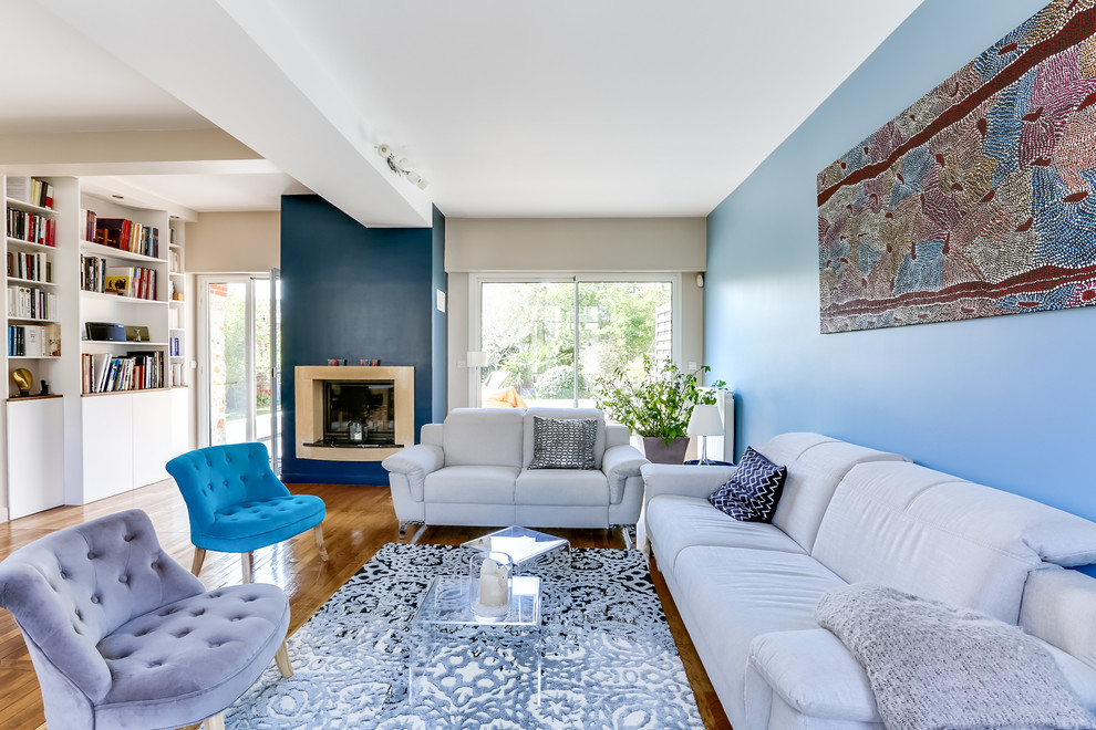 Inspiration for a large contemporary formal open concept living room in Paris with blue walls, light hardwood floors, a standard fireplace, a plaster fireplace surround and a wall-mounted tv.