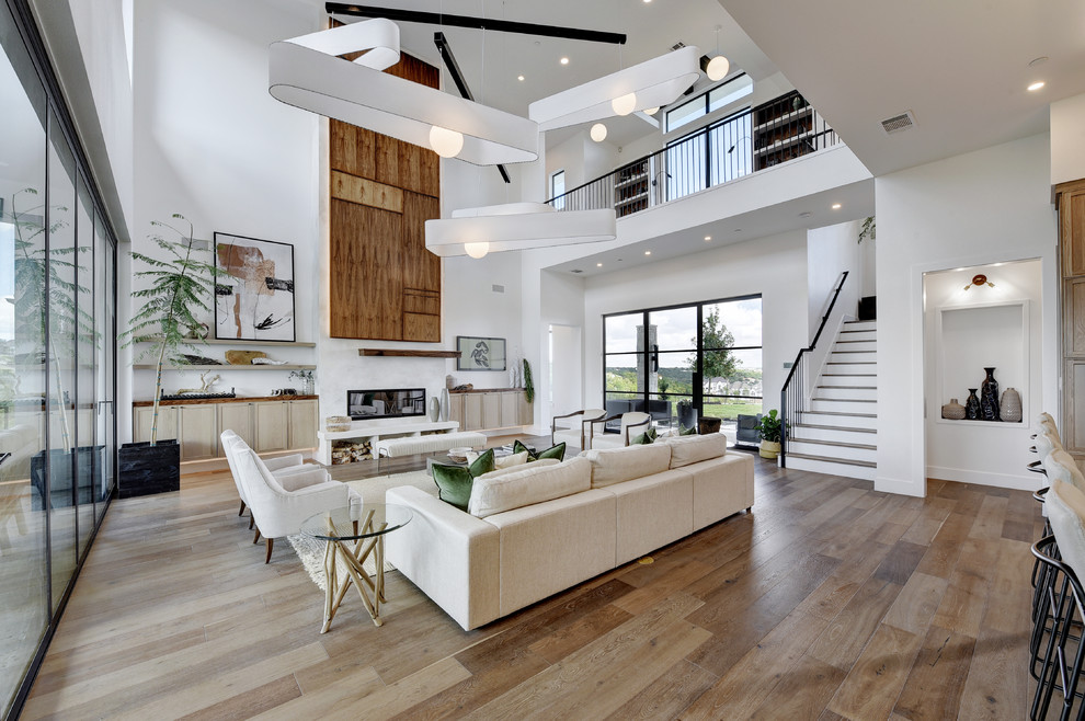 Inspiration for a contemporary open concept living room in Austin with white walls, medium hardwood floors, a ribbon fireplace and brown floor.