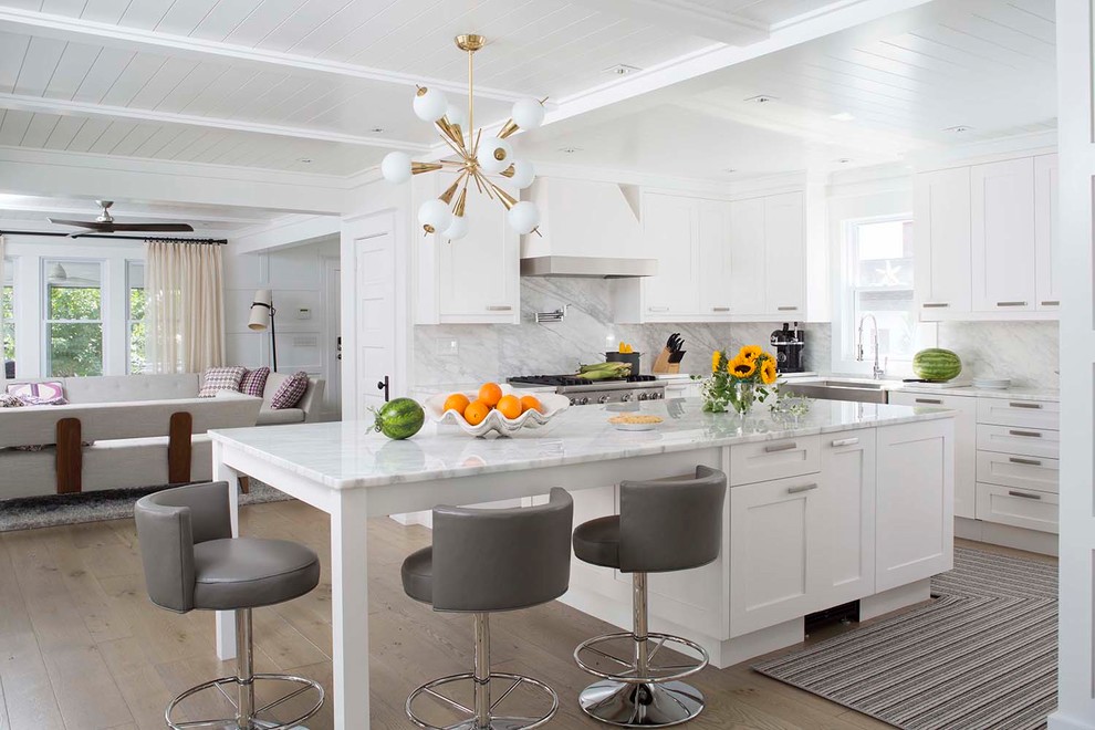 Design ideas for a transitional l-shaped open plan kitchen in Other with a farmhouse sink, shaker cabinets, white cabinets, stainless steel appliances, with island, beige floor, white benchtop and multi-coloured splashback.