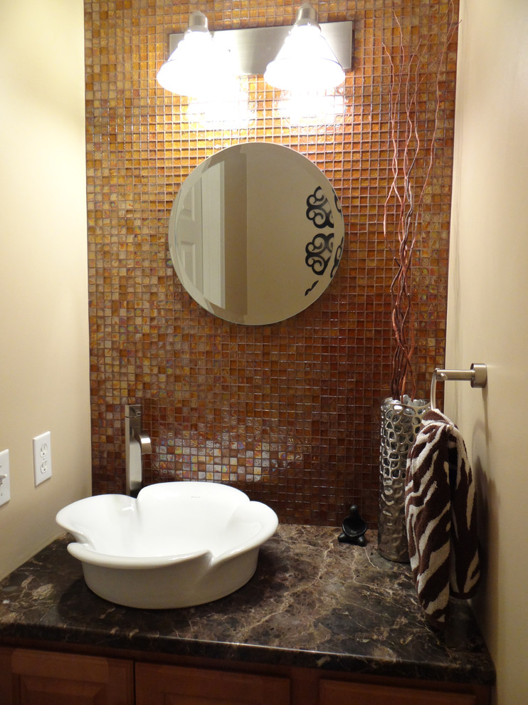 Small transitional brown tile and glass tile ceramic tile bathroom photo with a vessel sink, raised-panel cabinets, medium tone wood cabinets, marble countertops, a one-piece toilet and beige walls