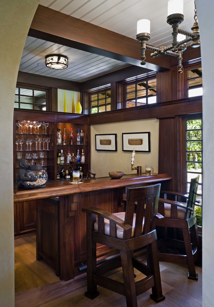 Inspiration for a mid-sized tropical galley seated home bar in Hawaii with dark hardwood floors, dark wood cabinets, wood benchtops, brown benchtop and open cabinets.