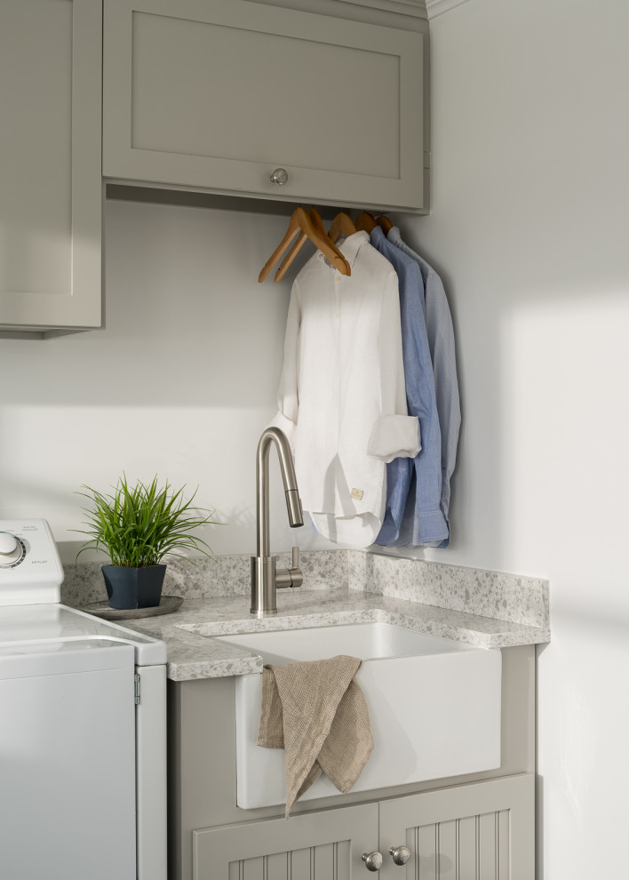 Photo of a beach style dedicated laundry room in Burlington with a farmhouse sink, shaker cabinets, quartz benchtops and a side-by-side washer and dryer.