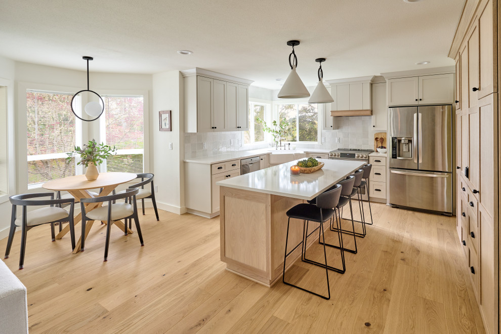 Inspiration for a mid-sized transitional light wood floor and beige floor kitchen remodel in Other with a farmhouse sink, recessed-panel cabinets, white cabinets, quartz countertops, white backsplash, ceramic backsplash, stainless steel appliances and white countertops