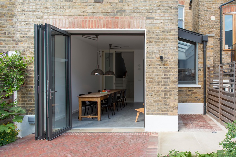 Mid-sized contemporary brick yellow townhouse exterior in London with a shed roof.