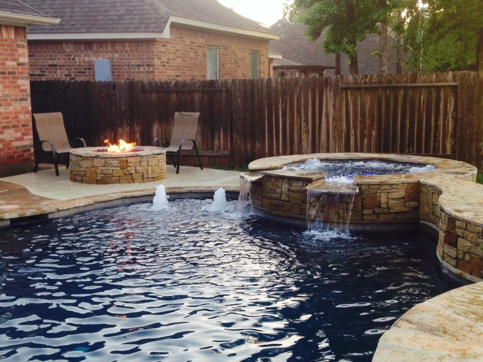 This is an example of a mid-sized country backyard custom-shaped lap pool in Houston with a hot tub and natural stone pavers.