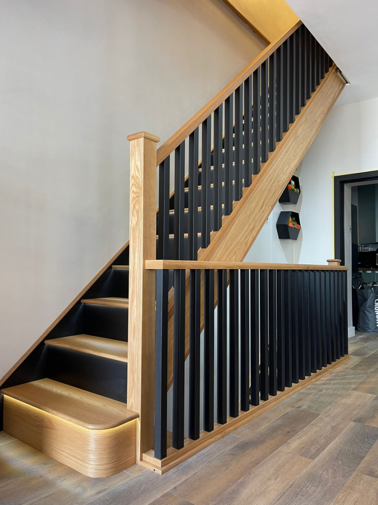 Imagen de escalera recta moderna grande con escalones de madera, contrahuellas de madera y barandilla de madera