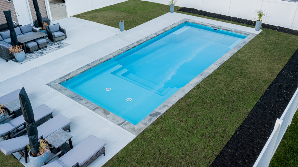 На фото: большой спортивный, прямоугольный ландшафтный бассейн на заднем дворе в современном стиле с мощением клинкерной брусчаткой