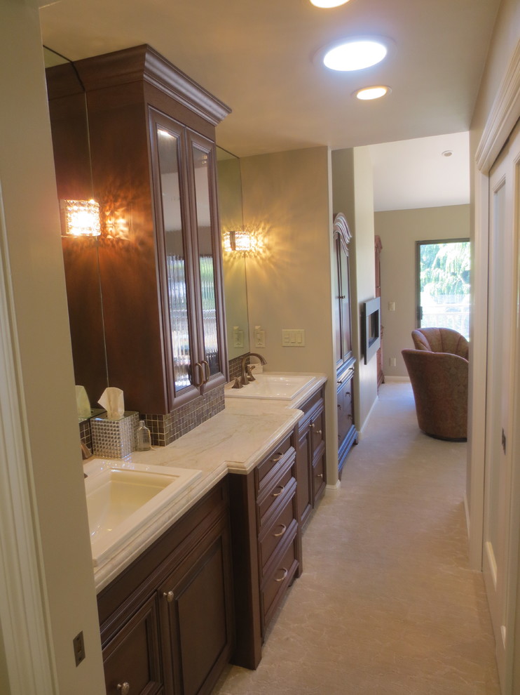 Design ideas for a large mediterranean master bathroom in San Francisco with a drop-in sink, raised-panel cabinets, dark wood cabinets, engineered quartz benchtops and brown tile.