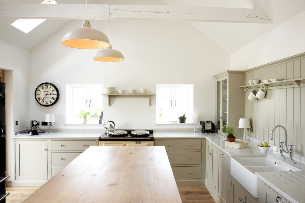 Country l-shaped kitchen in Other with a farmhouse sink, with island and beige cabinets.