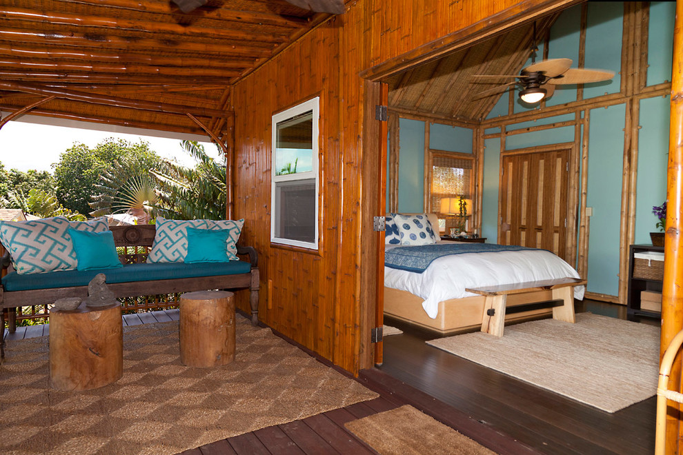 Photo of a tropical master bedroom in Hawaii with blue walls and dark hardwood floors.