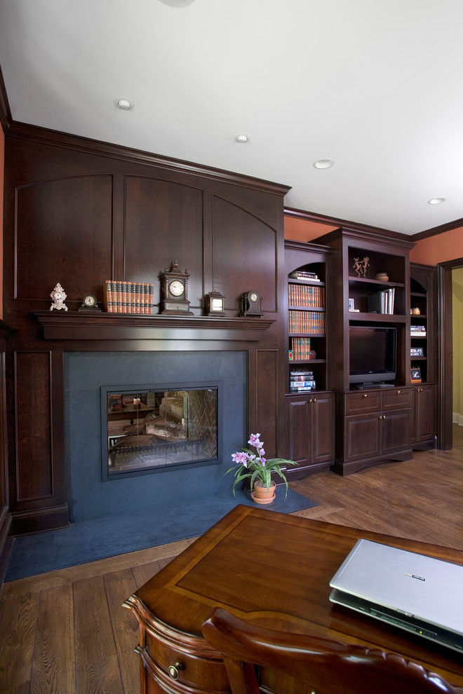 Inspiration for a large traditional open concept living room in Chicago with a library, orange walls, medium hardwood floors, a two-sided fireplace, a stone fireplace surround and a built-in media wall.