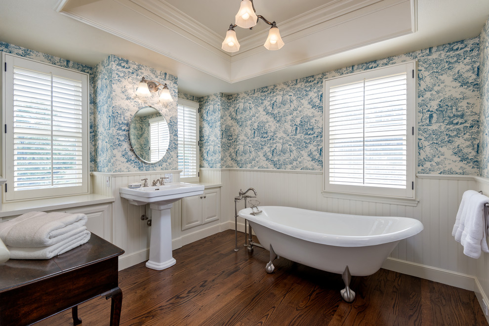 Photo of a traditional bathroom in San Francisco with a claw-foot tub, multi-coloured walls, dark hardwood floors, a pedestal sink and brown floor.