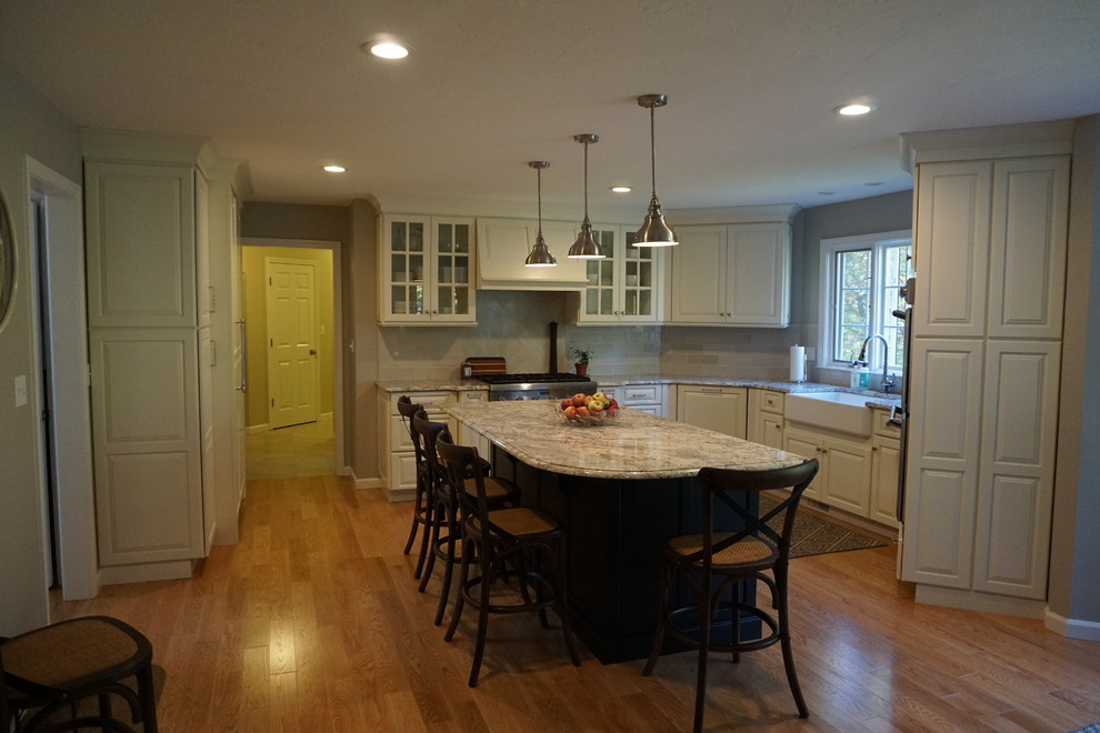 Large elegant l-shaped eat-in kitchen photo in Boston with a farmhouse sink, raised-panel cabinets, white cabinets, quartz countertops, white backsplash, ceramic backsplash, stainless steel appliances and an island