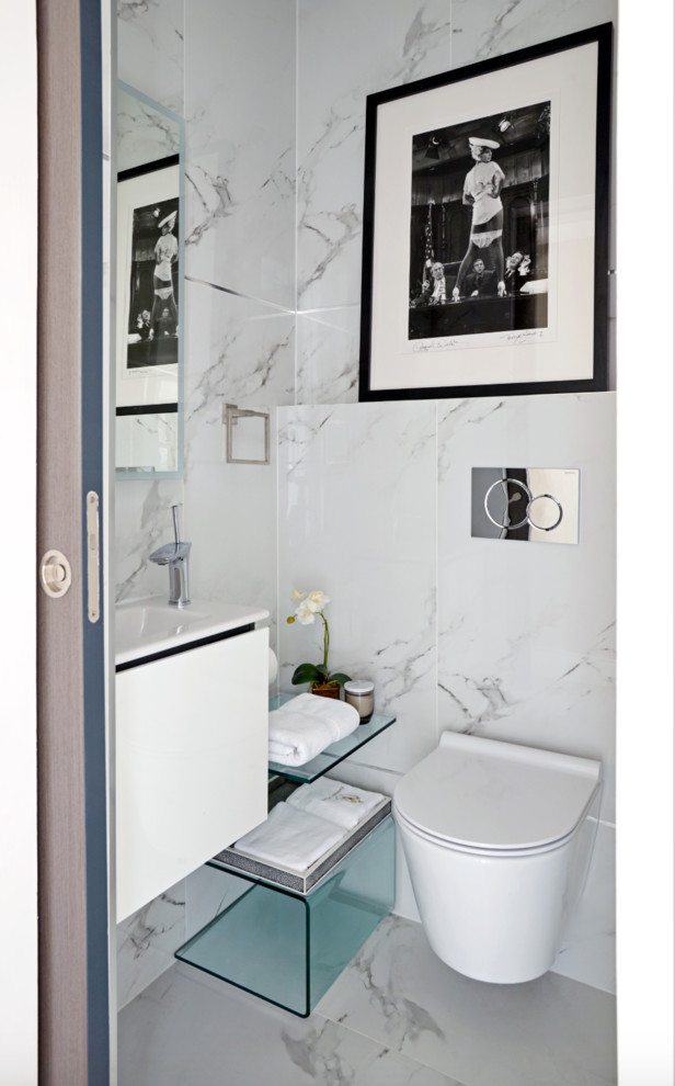Design ideas for a small modern powder room in Other with flat-panel cabinets, white cabinets, a wall-mount toilet, gray tile, white tile, marble, white walls, a wall-mount sink and white floor.