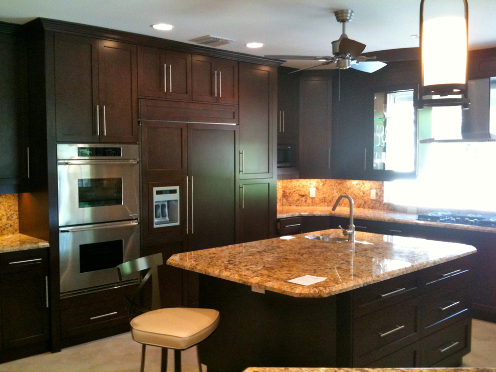 Open concept kitchen - large transitional u-shaped travertine floor and beige floor open concept kitchen idea in Miami with an undermount sink, shaker cabinets, dark wood cabinets, granite countertops, multicolored backsplash, stone tile backsplash, stainless steel appliances and an island